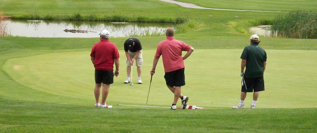 four players practicing putting